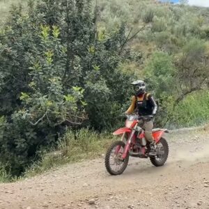 Enduro rider on a red dirt bike on a gravel trail, from Vanessa’s 350 versus 500 video