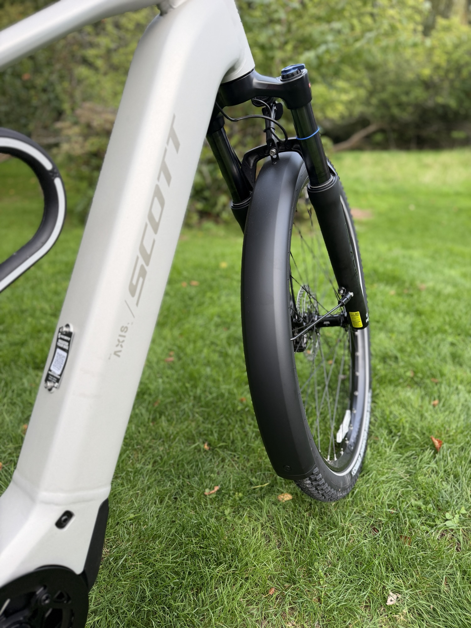 Close-up of a white SCOTT bike frame, front suspension fork and front wheel.
