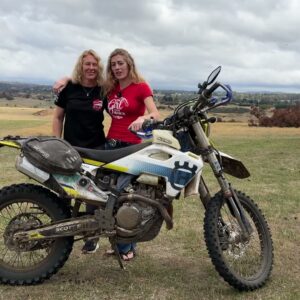 Vanessa Ruck and Kerry standing together behind a Husqvarna motorcycle in Tasmania