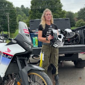 Vanessa Ruck holding the Cardo Venture helmet beside a Honda Transalp at Wailin’ Wayne